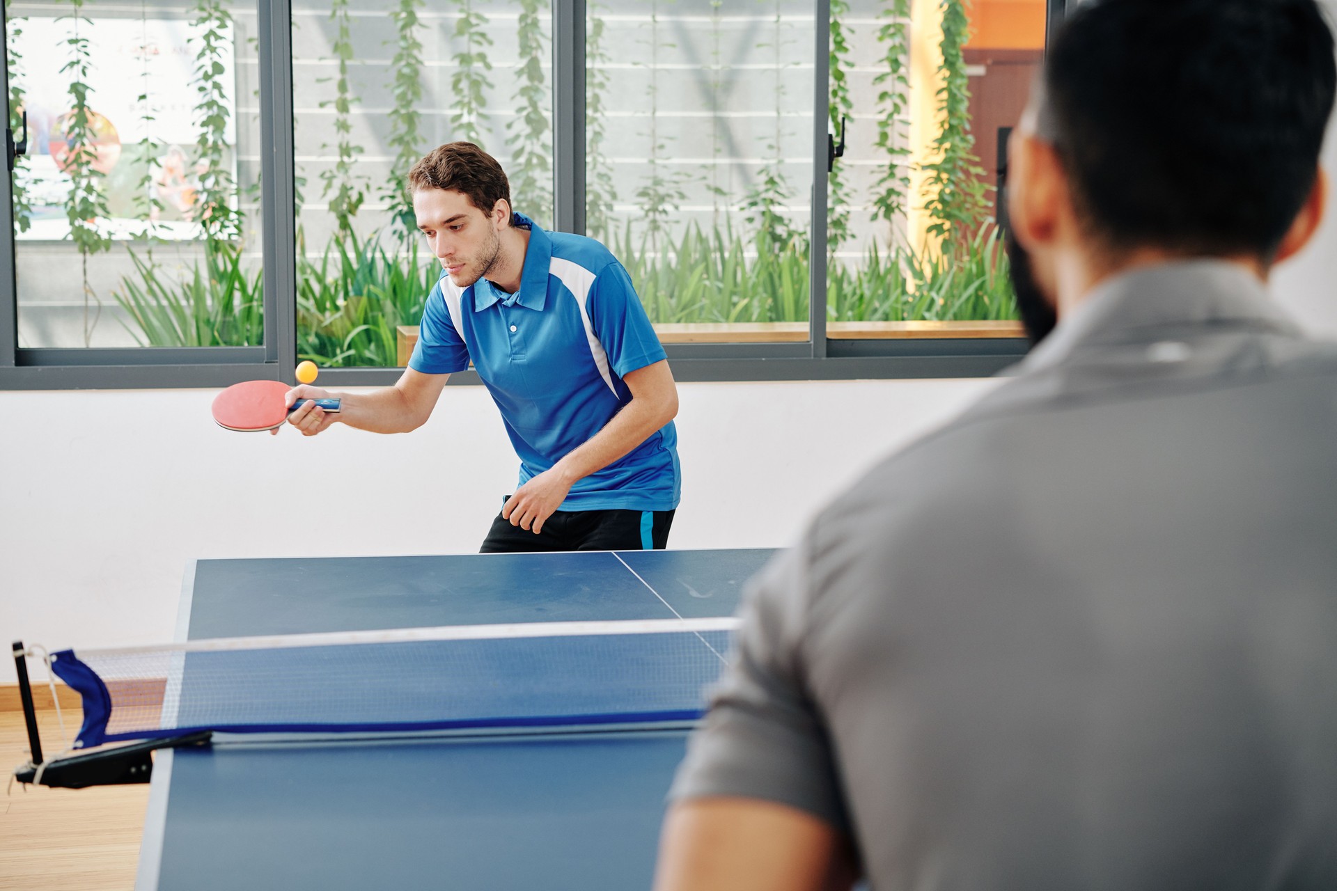 Mann spielt Tischtennis mit Freund